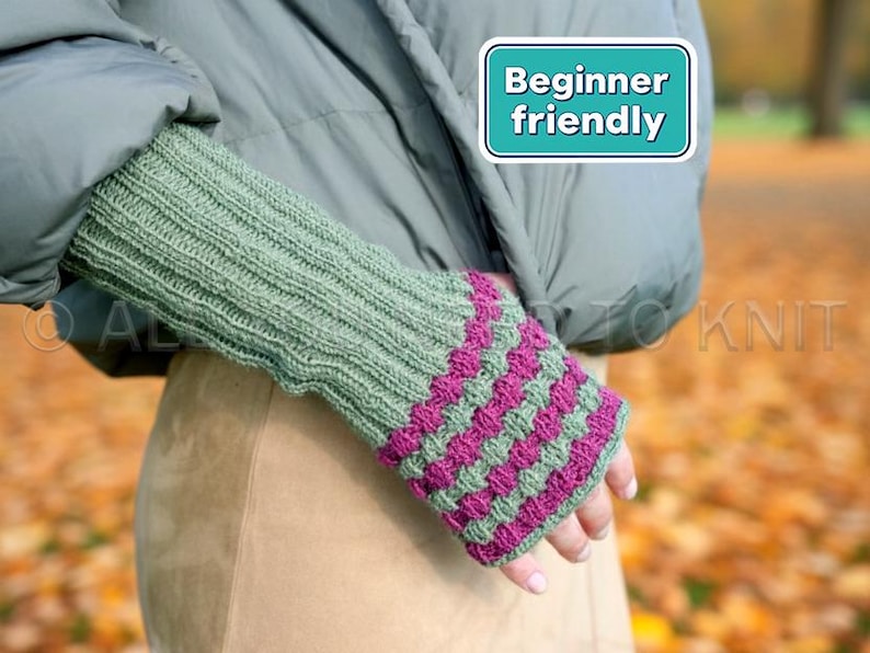 May include: Green and fuchsia knitted fingerless gloves. The gloves feature a ribbed design on the wrist and a textured pattern on the hand. The image includes a teal and white sign that says "Beginner friendly".
