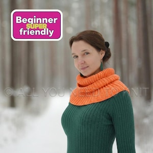 Peut inclure: Un cache-cou tricoté orange vif avec une texture côtelée porté sur un pull à manches longues côtelé vert foncé. Un graphique rectangulaire rose dans le coin supérieur gauche contient le texte blanc et jaune Beginner SUPER friendly.