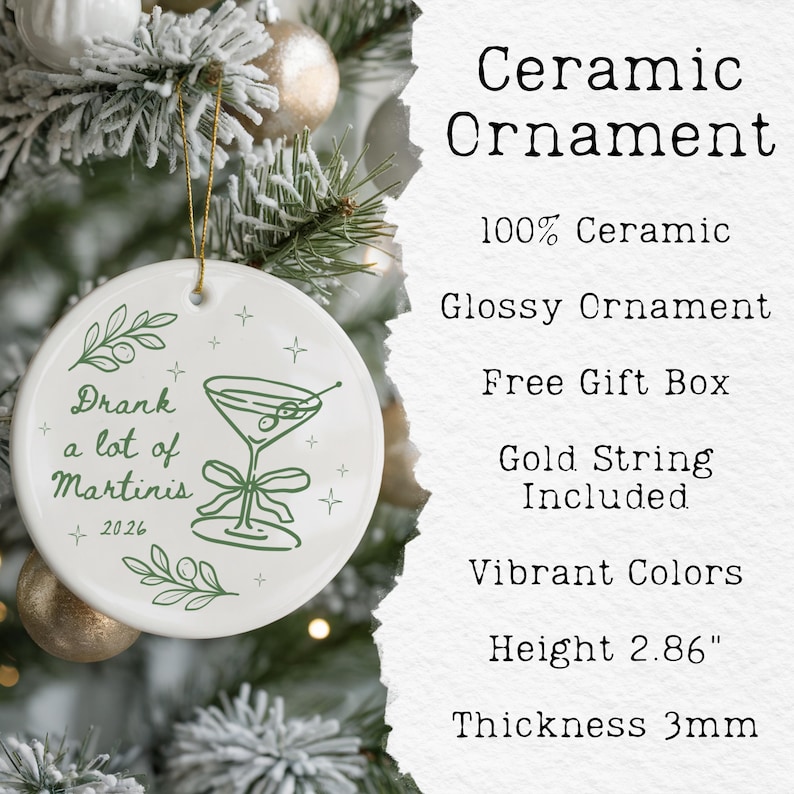 May include: A round white ceramic ornament with a glossy finish, featuring a green line-art illustration of a martini glass with olives and a bow. The text reads Drank a lot of Martinis and 2026. It includes a gold string and is 2.86 inches high.