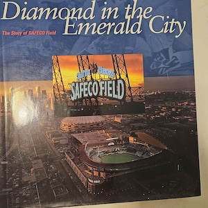 May include: A book cover featuring the title "Diamond in the Emerald City" and an image of Safeco Field, Seattle. The cover is predominantly blue with white text and a stadium photo.
