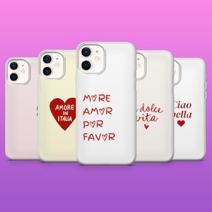 Op de afbeelding: Een verzameling witte telefoonhoesjes met verschillende rode tekstontwerpen. De ontwerpen bevatten zinnen als "Amore in Italia", "More Amor Por Favor", "Dolce Vita" en "Ciao Bella". Sommige hoesjes hebben ook een rood hartsymbool.