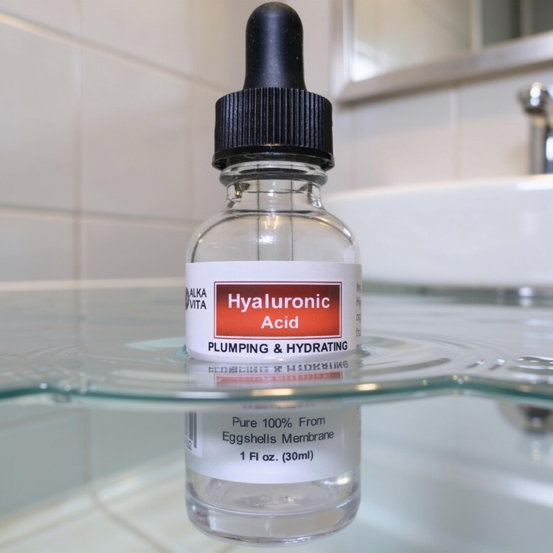 May include: A clear glass dropper bottle of Alka Vita Hyaluronic Acid serum with a black cap. The label reads Hyaluronic Acid, Plumping & Hydrating, and Pure 100% From Eggshells Membrane, 1 fl oz. The bottle is partially submerged in clear water.