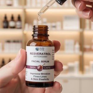 Puede incluir: Un frasco de vidrio marr&oacute;n de suero facial antioxidante Alka Vita Resveratrol con una etiqueta blanca que muestra una ilustraci&oacute;n de uva y texto que indica que mejora las arrugas, las l&iacute;neas finas y la elasticidad de la piel, con un gotero que dispensa un l&iacute;quido transparente.