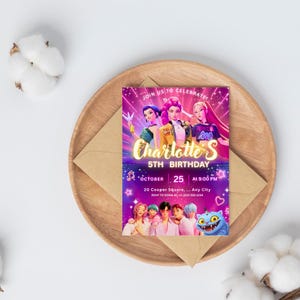May include: A birthday invitation with a vibrant design featuring animated characters. The invitation reads "Charlotte's 5th Birthday" with the date and time. The invitation is on a wooden tray with a brown envelope.