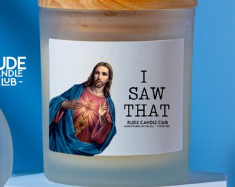 May include: A frosted glass candle jar with a wooden lid. The label features an image of Jesus and the text "I SAW THAT" with "RUDE CANDLE CLUB" branding. The background is a solid blue.