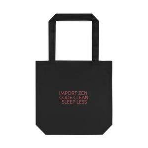 May include: Black tote bag with rectangular handles. The bag features the text "IMPORT ZEN CODE CLEAN SLEEP LESS" in a salmon colour. The bag is made of a sturdy material and is designed for carrying items.