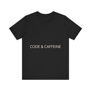 Puede incluir: Camiseta negra con el texto blanco "CODE & CAFFEINE" centrado en la parte delantera. La camiseta tiene mangas cortas y cuello redondo. La tela parece suave y cómoda.