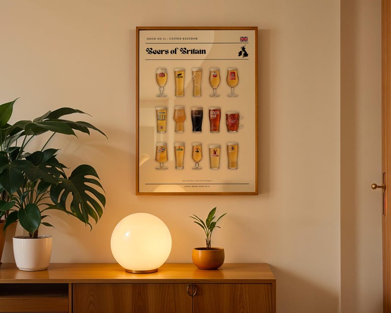 May include: A framed poster titled "Beers of Britain" displays illustrations of various beer glasses. The poster is mounted on a light-colored wall above a wooden cabinet. A round, white lamp and a potted plant are on the cabinet.