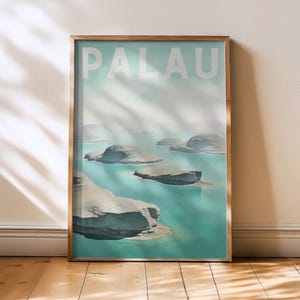 May include: A framed art print depicting a tranquil Palau landscape. The image shows turquoise water and rocky islands beneath a pale sky. The word "PALAU" is printed in large white letters at the top. The frame has a warm gold colour.