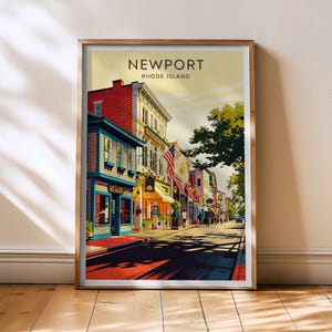 Può includere: Una stampa artistica incorniciata raffigurante una colorata scena di strada a Newport, Rhode Island. La stampa mostra edifici con facciate rosse, blu e gialle, con il testo "NEWPORT RHODE ISLAND" in alto. L'opera d'arte è esposta su un pavimento in legno.