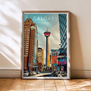 Può includere: Una stampa artistica incorniciata con un'illustrazione stilizzata di Calgary, Canada. L'opera mostra la Calgary Tower, gli edifici circostanti e il testo "CALGARY CANADA" in un design vibrante e colorato. La stampa è presentata in una cornice dorata.
