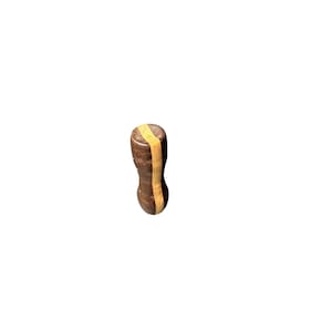 May include: A brown wooden bottle stopper with a vertical, light-colored stripe down the center. The stopper has a rounded top and a slightly hourglass shape. The light stripe is a contrasting color to the darker brown wood.