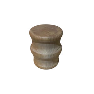 May include: A small, light brown wooden stool with a rounded top and a cylindrical, layered body. The wood grain is visible, giving it a natural, rustic appearance. The stool is designed with a simple, yet elegant shape.