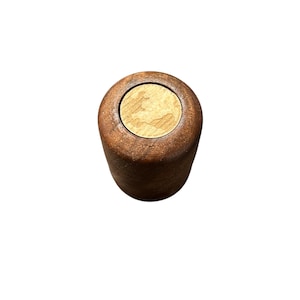 Puede incluir: Un tapón de botella de madera con una parte superior de corcho. El tapón es cilíndrico con un acabado marrón oscuro. El corcho es de color marrón claro con un patrón de vetas de madera natural. El tapón está diseñado para encajar en una botella.