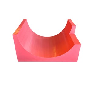 Peut inclure: Un objet semi-circulaire de couleur corail vif, avec une base plate et un intérieur incurvé. L'objet a une finition lisse et mate et une extension rectangulaire sur un côté. Le design est simple et moderne, sur fond blanc.