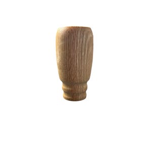 May include: A wooden furniture leg with a light brown finish. The leg has a cylindrical shape with a flared top and a decorative, rounded base. The wood grain is visible, adding texture to the piece. This leg is suitable for various furniture projects.