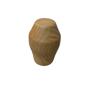 May include: A light brown wooden cabinet knob with a textured top and a rounded, tapered shape. The knob is made of natural wood and is designed for use on drawers or cabinet doors.