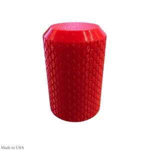 May include: A bright red, cylindrical object with a textured, scale-like pattern. The top is flat and slightly angled. The object is a solid, vibrant red color and appears to be made of plastic or a similar material.