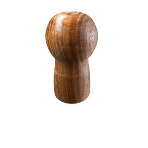May include: A wooden bottle stopper with a rounded top and a cylindrical base. The stopper is made of a dark brown wood with visible grain patterns. The design is simple and elegant.