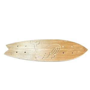 Könnte beinhalten: Ein hellbraunes Holz-Skateboard mit einem eingravierten Wal-Design. Das Board hat eine abgerundete Form mit einem Heckflügel und vorgebohrten Löchern. Der Wal ist in einer einfachen, stilisierten Form dargestellt. Es ist etwa 76 cm lang.