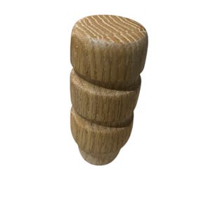 May include: A light-colored wooden furniture leg with a cylindrical shape. The leg has a rounded top and a series of stacked, textured rings. The wood grain is visible, adding to the natural aesthetic. The leg is designed for furniture.