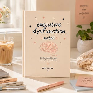 Peut inclure: Un livre à couverture rigide de couleur crème intitulé Executive Dysfunction Notes par Gwen Carter. La couverture présente un texte bleu foncé, un dessin au trait corail représentant un cerveau et des étoiles. Le sous-titre indique for the thoughts, tasks & everything in between.