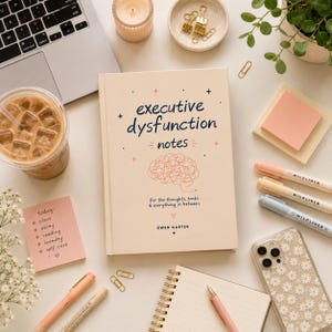 Puede incluir: Un libro de tapa dura color crema titulado Executive Dysfunction Notes de Owen Carter, con un dibujo lineal de un cerebro, rodeado por una computadora port&aacute;til, caf&eacute; helado, notas adhesivas, resaltadores, una funda de tel&eacute;fono con margaritas y suministros.