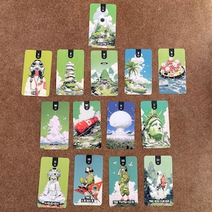 May include: A collection of fourteen rectangular tarot-style cards arranged in a spread. Each card features distinct, colorful illustrations of figures, landscapes, and objects, with some cards displaying text labels like BREATH, BACKCASSIE, and THE RECOLOGIST.