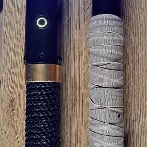 May include: Two lightsabers with illuminated blades. One has a black braided handle and gold accents, the other has a grey wrapped handle. The blades glow blue and green.