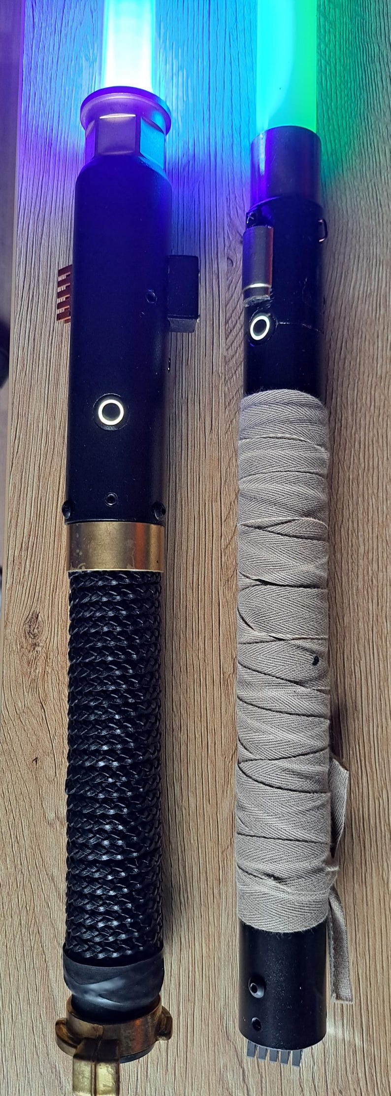 May include: Two lightsabers with illuminated blades. One has a black braided handle and gold accents, the other has a grey wrapped handle. The blades glow blue and green.