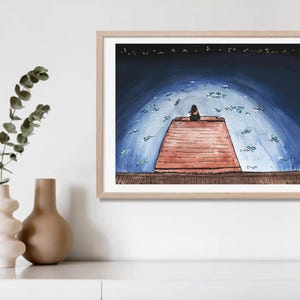 May include: Framed art print. The watercolour illustration shows a person seated on a red structure beneath a blue sky with white shapes. The print is in a light wood frame, displayed on a white surface.