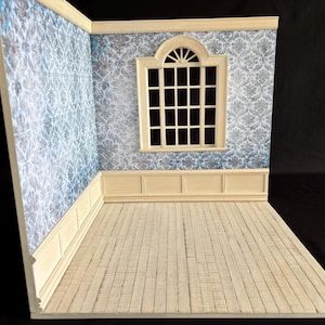 May include: A miniature room diorama with light wood flooring and pale yellow trim. The walls are covered in a blue and white floral wallpaper. A window with a black grid is centered on one wall.