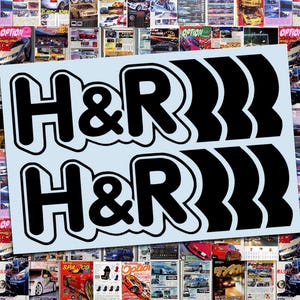 May include: Two black and white H&R logo stickers on a light blue background, set against a collage of car magazine covers. The stickers feature the H&R logo in a bold, outlined font with a series of curved lines.