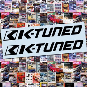 May include: A light blue sticker with the words "K-TUNED" in bold black letters. The sticker has a background of various car magazines. The "K" is stylized with a chevron design.