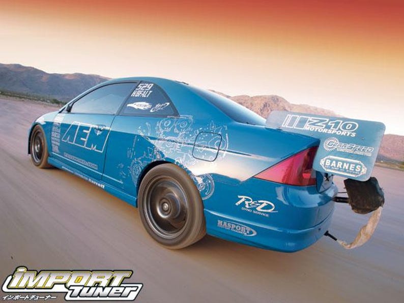 May include: A blue sports car with a large rear wing and custom graphics. The car has black wheels and various sponsor logos, including "AEM" and "Import Tuner". The background shows a desert landscape.