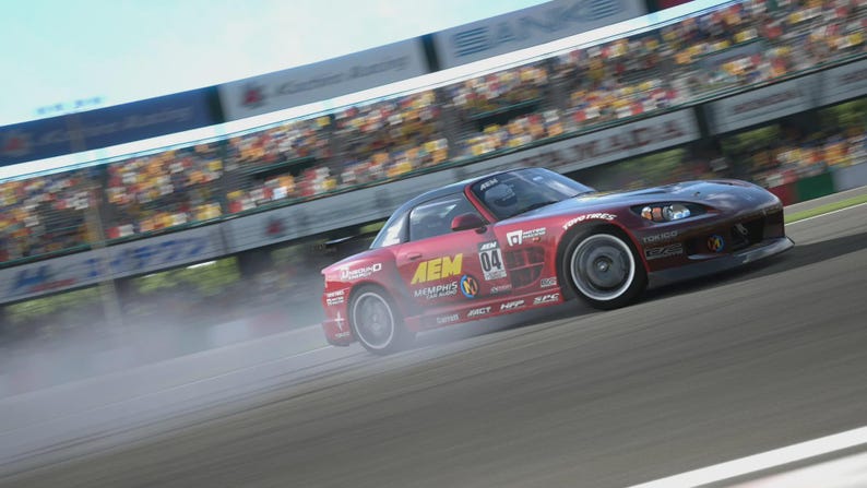 May include: A red sports car with black accents drifts on a racetrack, kicking up a cloud of smoke. The car has the number 04 on the side and sponsor logos. A grandstand with spectators is visible in the background.