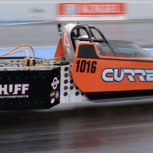 May include: An orange and black dragster with the text "CURRENT TECHNOLOGY" and the number "1016" on the side. The dragster has large rear tires and small front tires. The vehicle is on a racetrack.