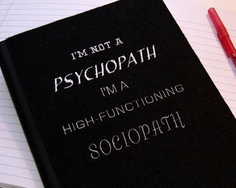 May include: A black notebook with the text "I'm not a psychopath I'm a high-functioning sociopath" written in white.