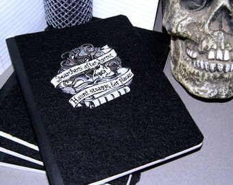 May include: A black notebook with a white design featuring a skull and the text "Searchers after horror haunt strange, far places".