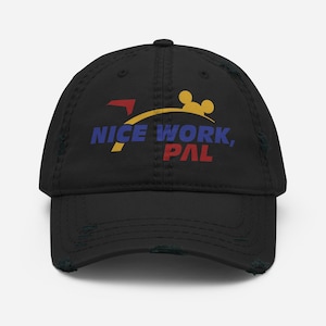 以下が含まれることがあります： 黒色のダメージ加工ベースボールキャップ。青と赤で「NICE WORK, PAL」の文字がプリントされています。デザインには、ミッキーマウスのようなシルエットの黄色いアーチが含まれています。キャップは使い古されたヴィンテージ感があります。