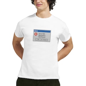 Könnte beinhalten: Weißes T-Shirt mit einem humorvollen Grafik-Design einer Fehlermeldung. Die Meldung lautet "Error 404: Motivation Not Found" in einem simulierten Computerfenster. Das Design enthält die Schaltflächen "OK" und "Abbrechen".