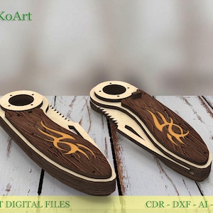 May include: Two laser-cut wooden pocket knife designs. The knives have a dark brown wood grain centre with an orange tribal design. The handles are light-coloured wood. The text "EstetiKoArt" is in the upper left corner. The text "LASER CUT DIGITAL FILES" is at the bottom.