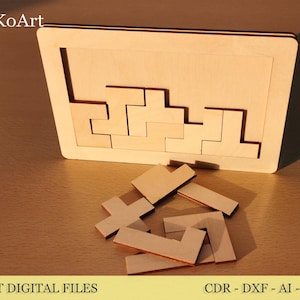 Op de afbeelding: Een houten puzzel met een rechthoekig frame en verschillende geometrische stukken. Sommige stukken zitten in het frame, andere liggen verspreid in de buurt. De tekst "EsTetiKoArt" staat linksboven. De tekst "LASER CUT DIGITAL FILES" staat onderaan.