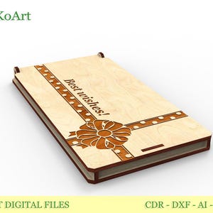 May include: A light brown wooden box with a laser-cut design. The box features a ribbon design and the words "Best wishes!". The box has darker brown accents and is suitable for gifts or keepsakes.