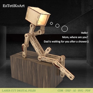 May include: A wooden laser-cut lamp in the shape of a person sitting on a wooden block. The lamp's head is a box that emits light. Text on the image says, "Hello! Mom, where are you? Dad is waiting for you after a shower)"