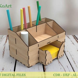 May include: A laser-cut wooden desk organizer with multiple compartments for pens, pencils, and other office supplies. The organizer has a small drawer with yellow sticky notes. The text "EsTetiKoArt" and "LASER CUT DIGITAL FILES" are visible.