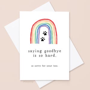 May include: A white card with a rainbow and paw prints, with the text "saying goodbye is so hard. so sorry for your loss." The card is inside a white envelope. The rainbow has red, orange, yellow, green, blue, and purple stripes.