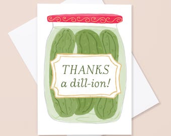 May include: A white greeting card featuring a jar of pickles with a red lid and the text "THANKS a dill-ion!" in a decorative frame. The card is on a white envelope, perfect for sending a thank you note.