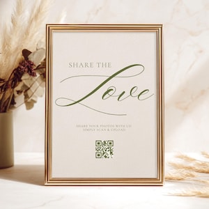 May include: A rectangular gold-toned picture frame containing a sign with a cream background. The text reads "SHARE THE Love" in dark green, followed by "SHARE YOUR PHOTOS WITH US! SIMPLY SCAN & UPLOAD." and a square green QR code at the bottom.