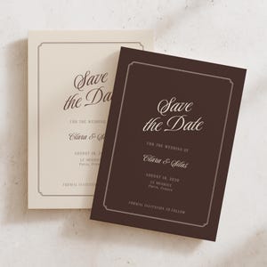 Könnte beinhalten: Zwei rechteckige Save-the-Date-Karten mit einem dünnen dekorativen Rand. Eine Karte ist dunkelbraun mit weißem Text, die andere cremefarben mit dunkelbraunem Text. Beide Karten zeigen die Namen Clara & Silas, das Datum und den Veranstaltungsort.